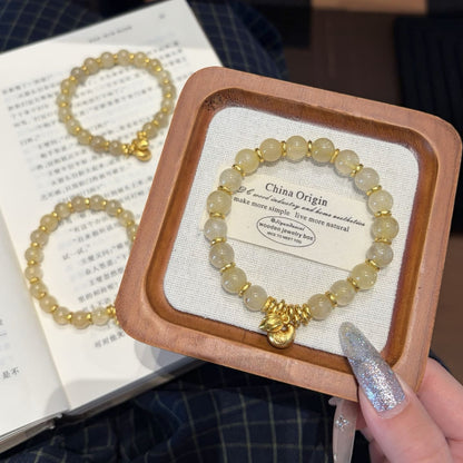 Handmade gold rutile beaded bracelet with natural healing crystal beads, held in hand for display
