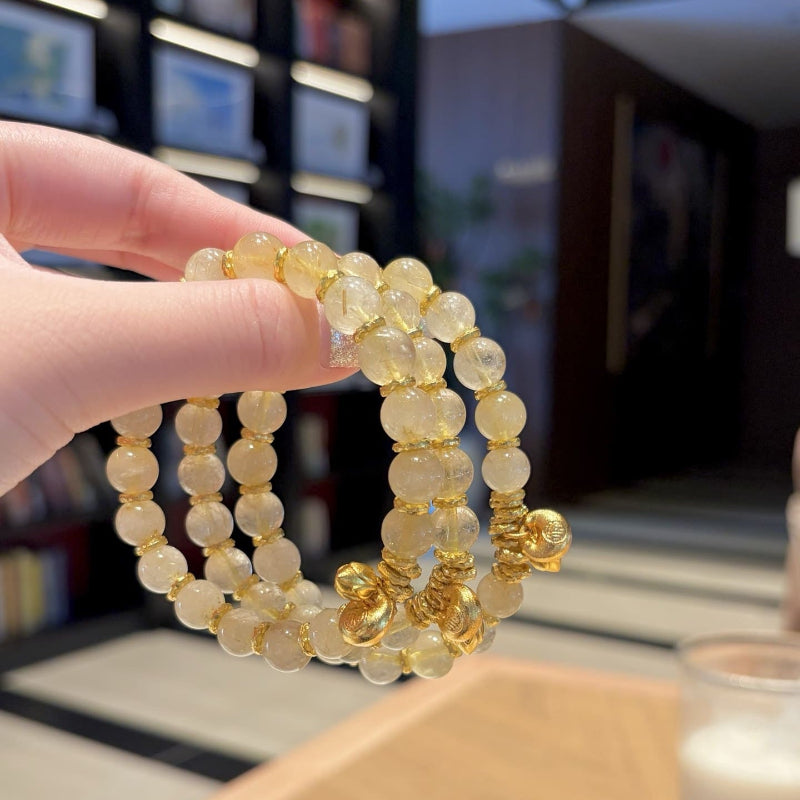 Handmade gold rutile beaded bracelet with natural healing crystal beads, held in hand for display