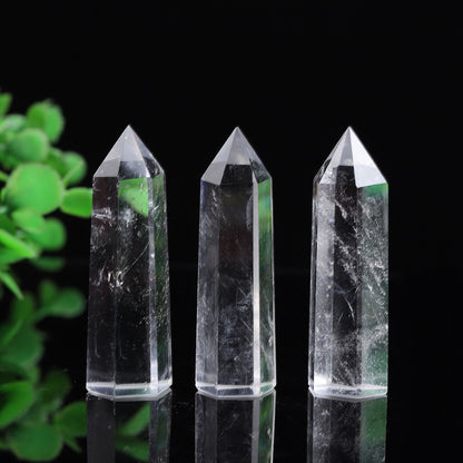 Natural clear quartz crystal tower point, polished transparent hexagonal quartz wand with green plant background
