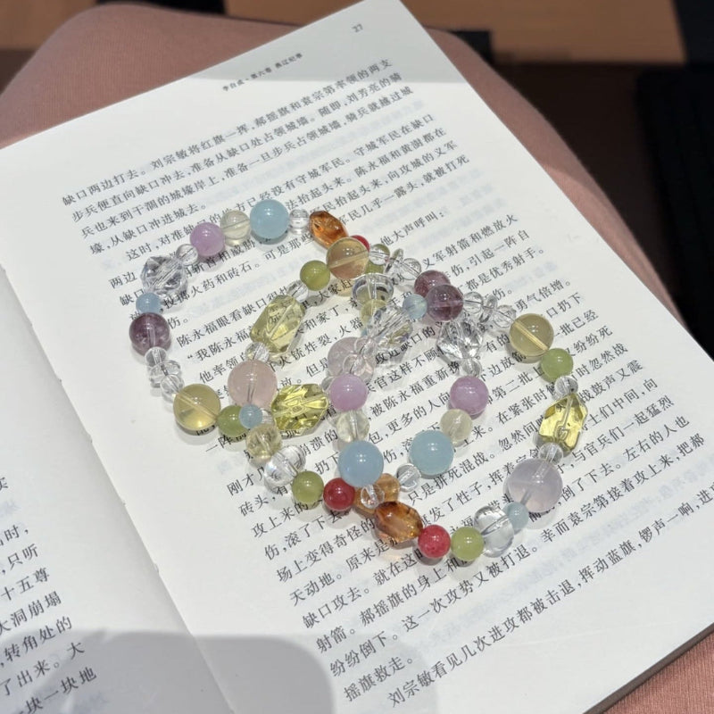 Handmade multicolor crystal bracelet featuring citrine and clear quartz beads, held in hand.
