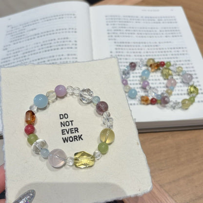 Handmade multicolor crystal bracelet featuring citrine and clear quartz beads, held in hand.