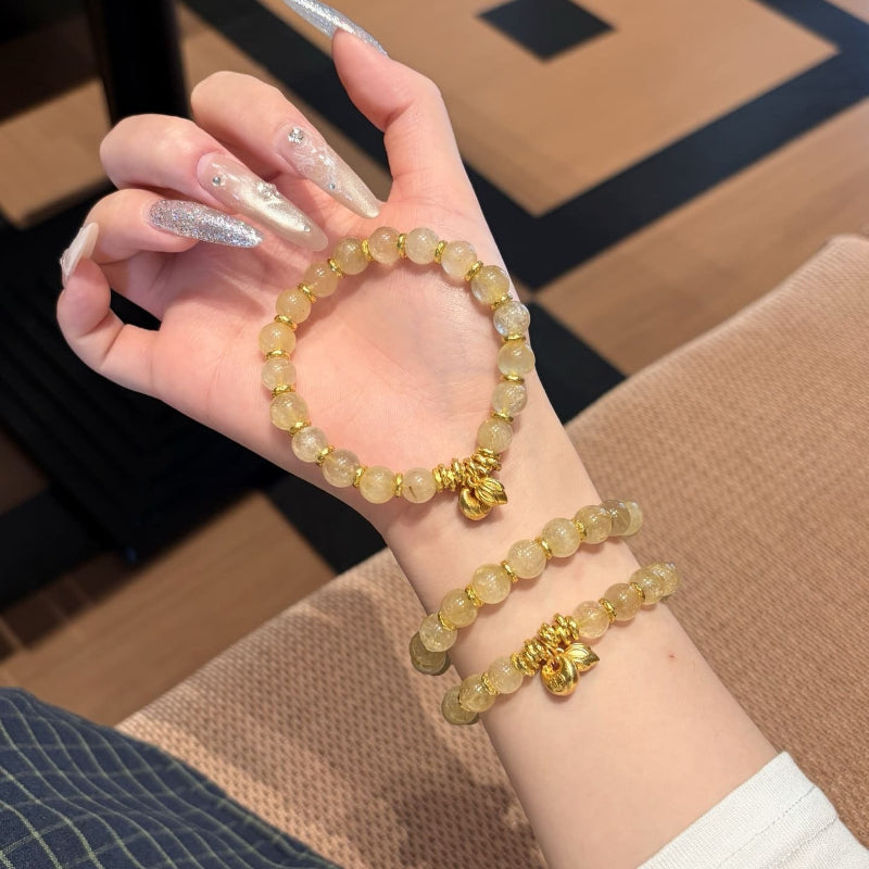 Handmade gold rutile beaded bracelet with natural healing crystal beads, held in hand for display