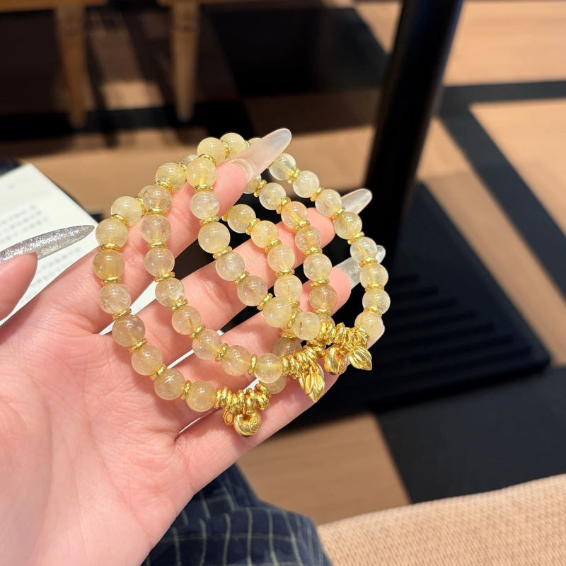 Handmade gold rutile beaded bracelet with natural healing crystal beads, held in hand for display