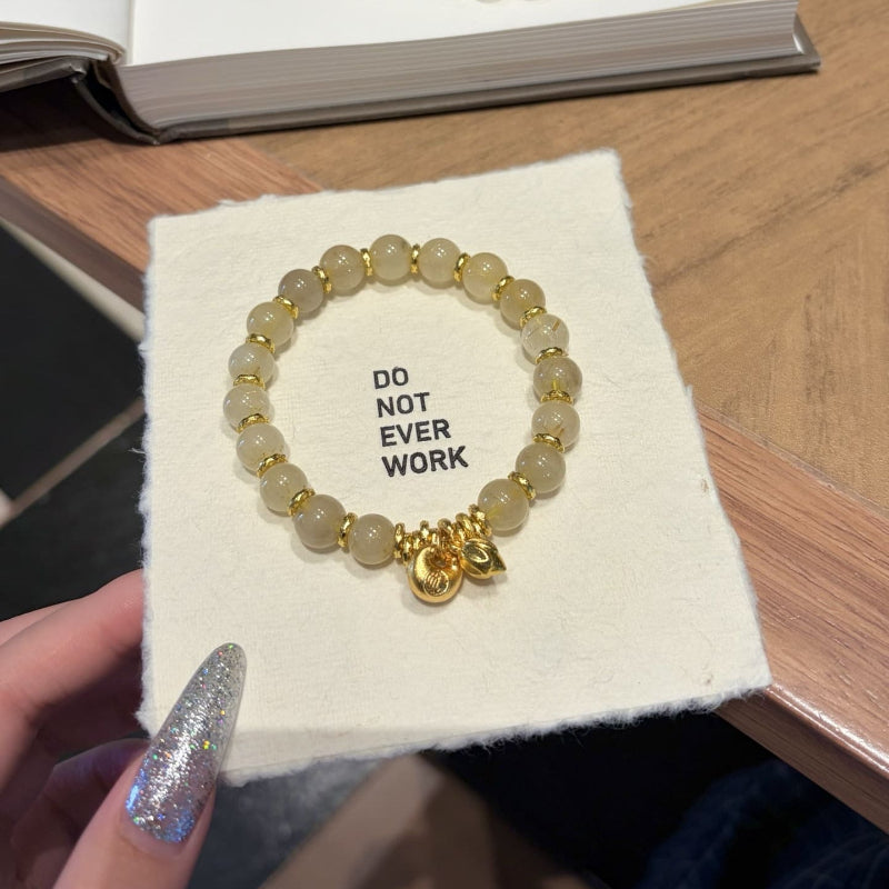 Handmade gold rutile beaded bracelet with natural healing crystal beads, held in hand for display