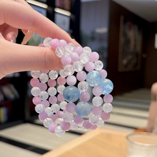 Handmade purple spodumene and aquamarine crystal bracelet, held in hand for display