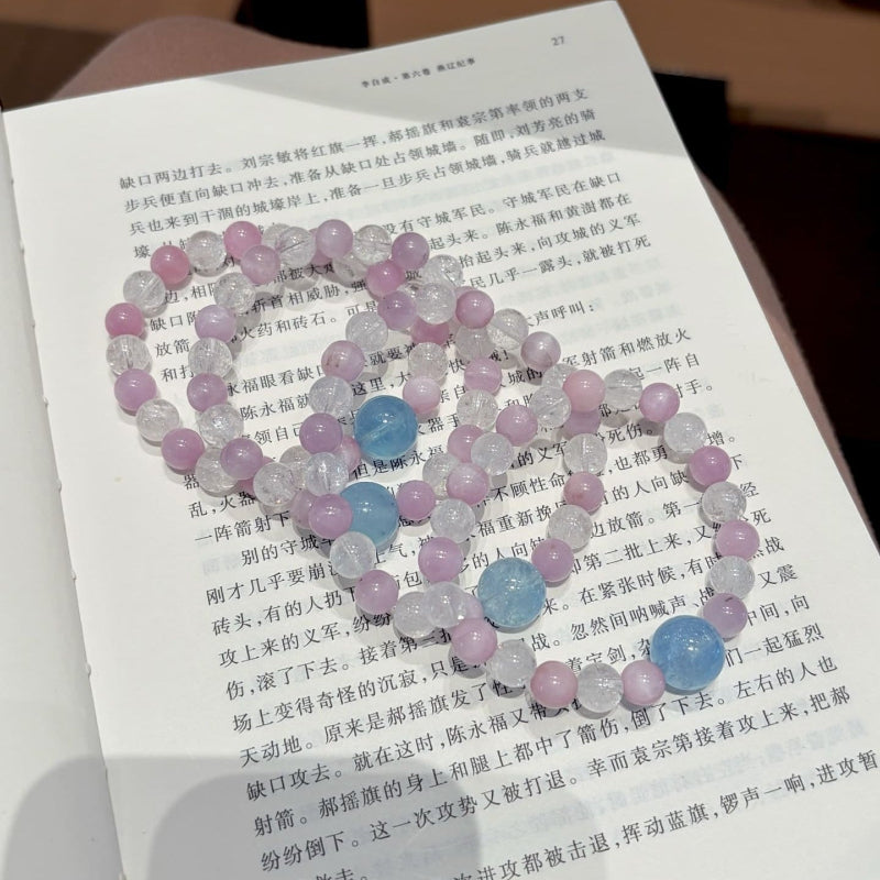 Handmade purple spodumene and aquamarine crystal bracelet, held in hand for display