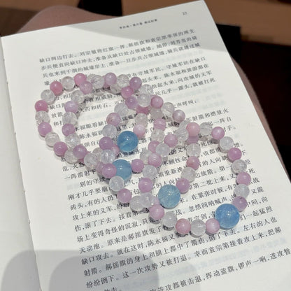 Handmade purple spodumene and aquamarine crystal bracelet, held in hand for display