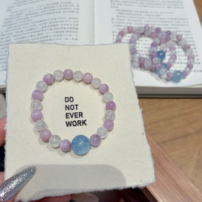 Handmade purple spodumene and aquamarine crystal bracelet, held in hand for display