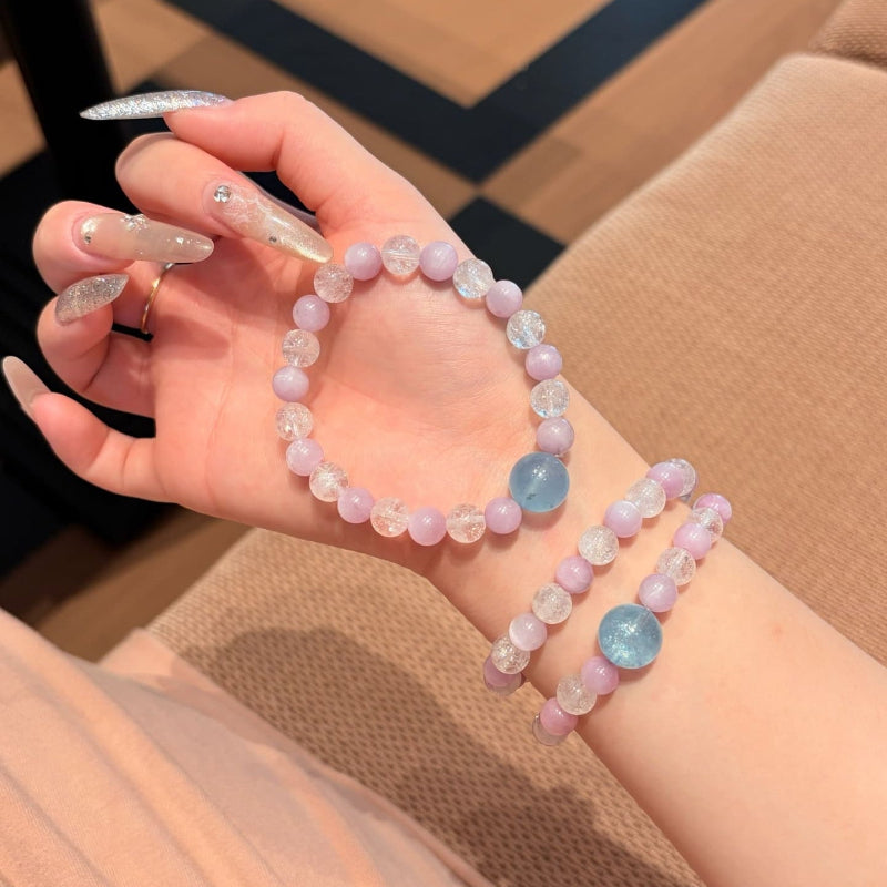 Handmade purple spodumene and aquamarine crystal bracelet, held in hand for display