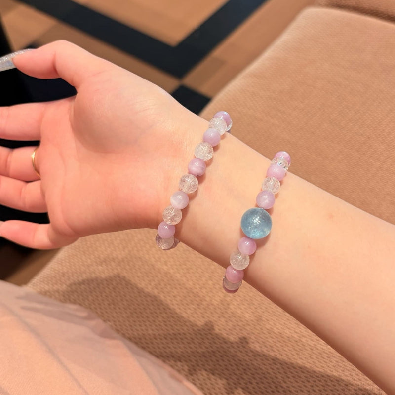 Handmade purple spodumene and aquamarine crystal bracelet, held in hand for display