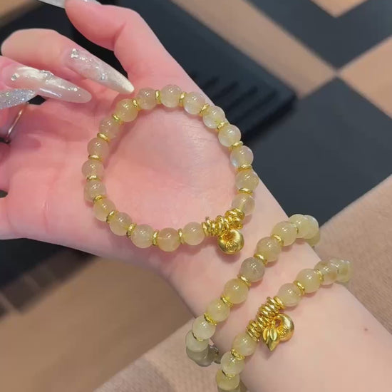Handmade gold rutile beaded bracelet with natural healing crystal beads, held in hand for display