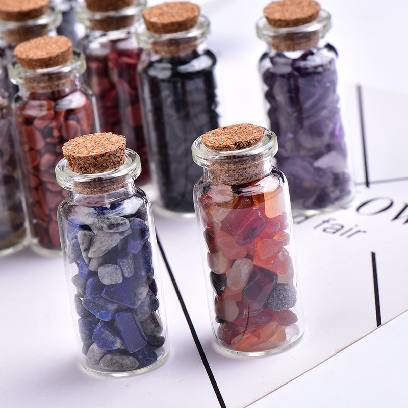 Close up of mini glass wishing bottles with natural crystal chips, healing tumbled gemstone fragments with cork stopper